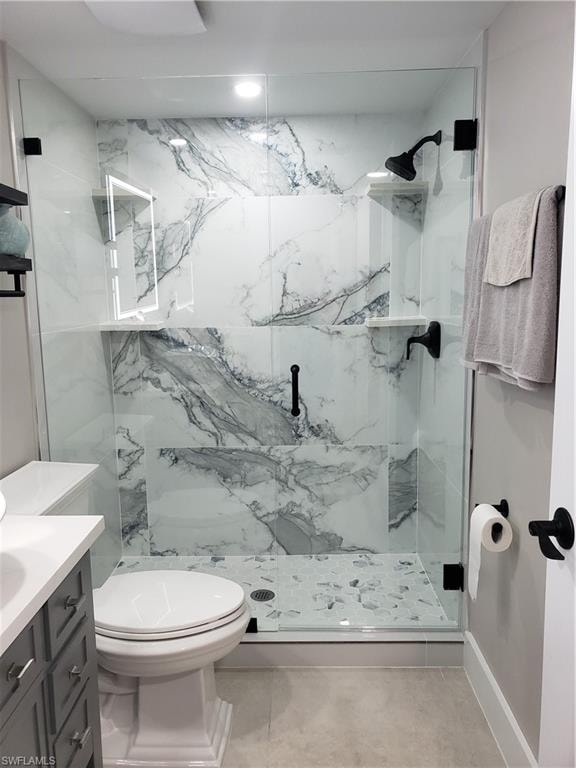 Guest Bathroom featuring toilet, a marble finish shower, and vanity