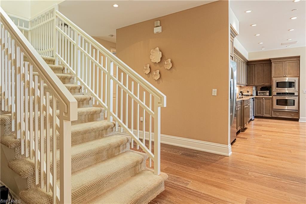 Staircase featuring baseboards, wood finished floors, and recessed lighting
