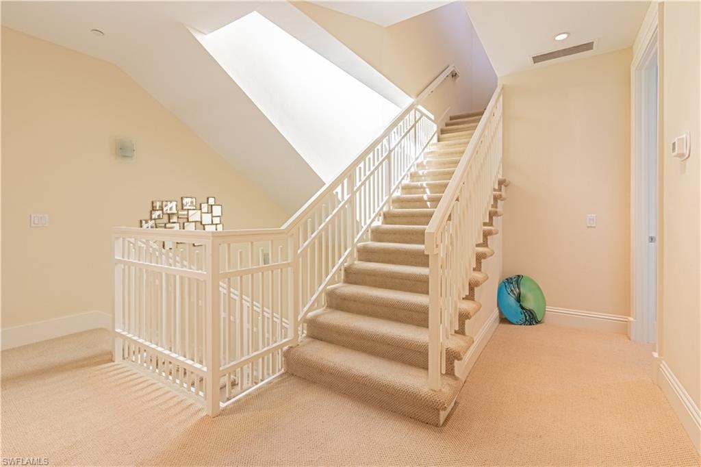 Stairway with carpet flooring, visible vents, vaulted ceiling, and baseboards