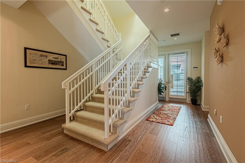Foyer featuring hardwood / wood-style flooring, visible vents, stairs, and baseboards