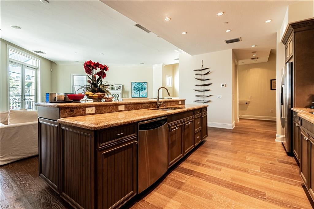 Kitchen with stainless steel appliances, visible vents, light wood-style floors, open floor plan, and a sink