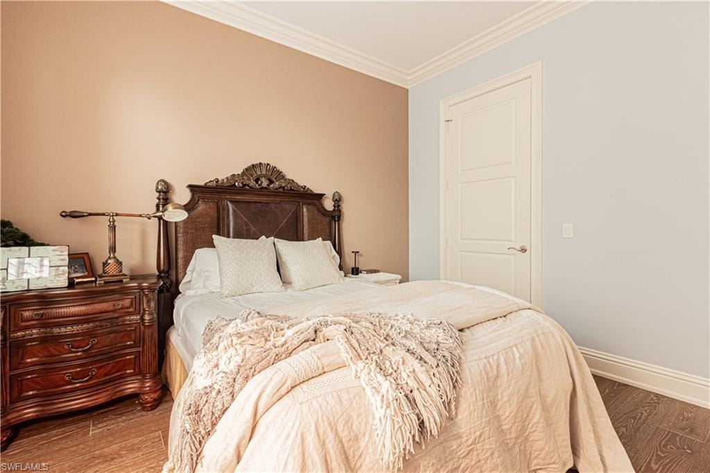 Bedroom featuring ornamental molding, baseboards, and wood finished floors