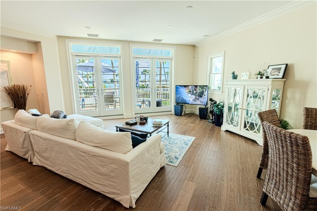 Living area with visible vents, ornamental molding, wood finished floors, and a wealth of natural light