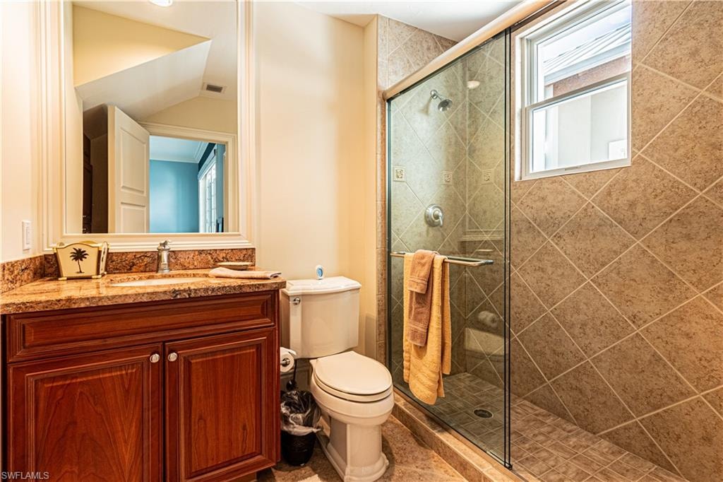 Full bathroom featuring visible vents, toilet, vaulted ceiling, a shower stall, and vanity