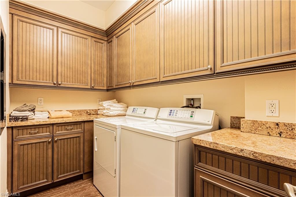 Clothes washing area featuring light wood-type flooring, cabinet space, and washer and dryer