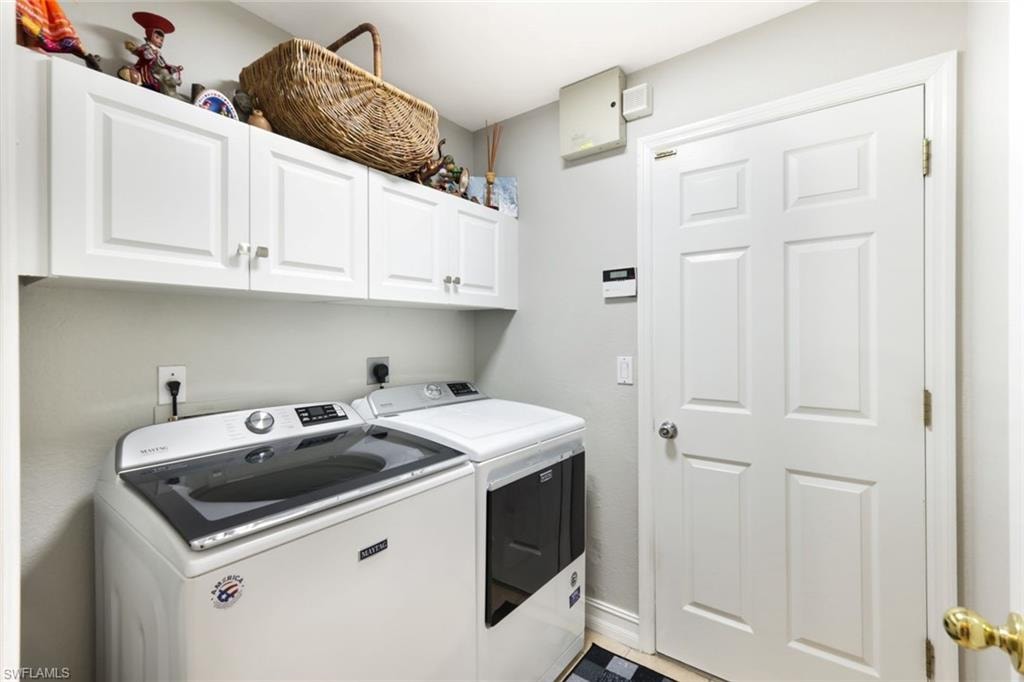 Washroom with cabinet space, baseboards, and separate washer and dryer