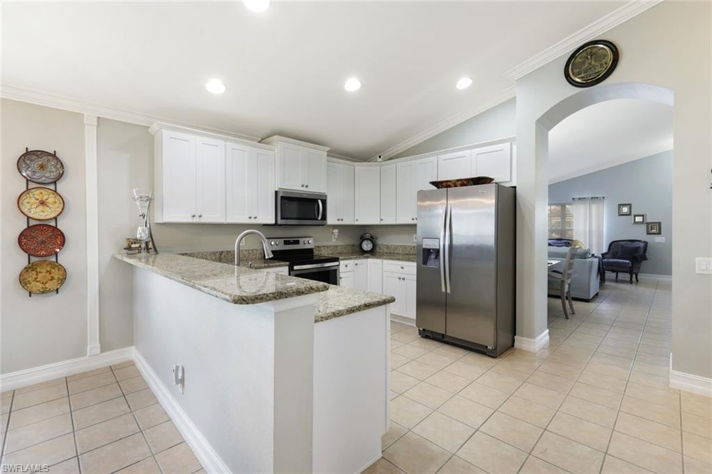 Kitchen with light tile patterned floors, arched walkways, white cabinets, a peninsula, and stainless steel appliances