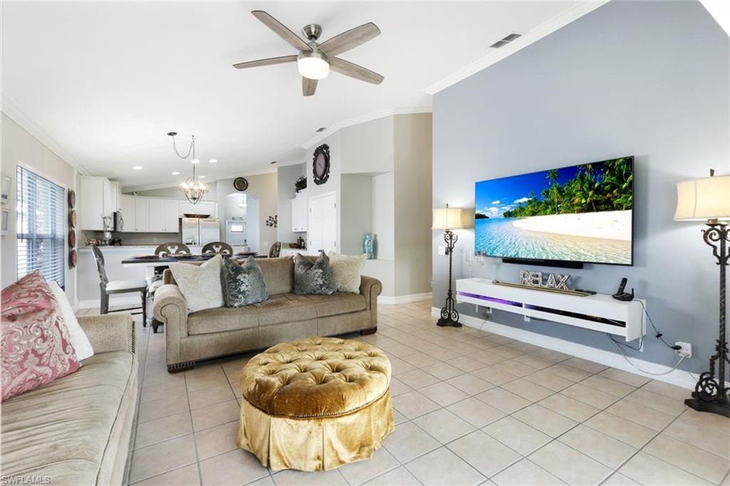 Living area featuring baseboards, light tile patterned flooring, visible vents, and crown molding