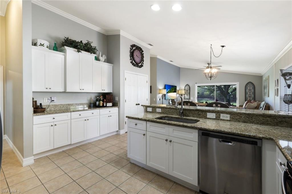 Kitchen with lofted ceiling, ornamental molding, white cabinetry, a sink, and dishwasher