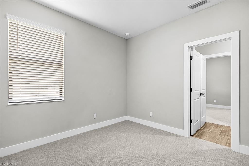 Unfurnished room with light colored carpet and baseboards
