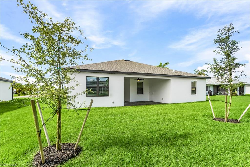 Rear view of house with a lawn, a patio area, a ceiling fan, and stucco siding