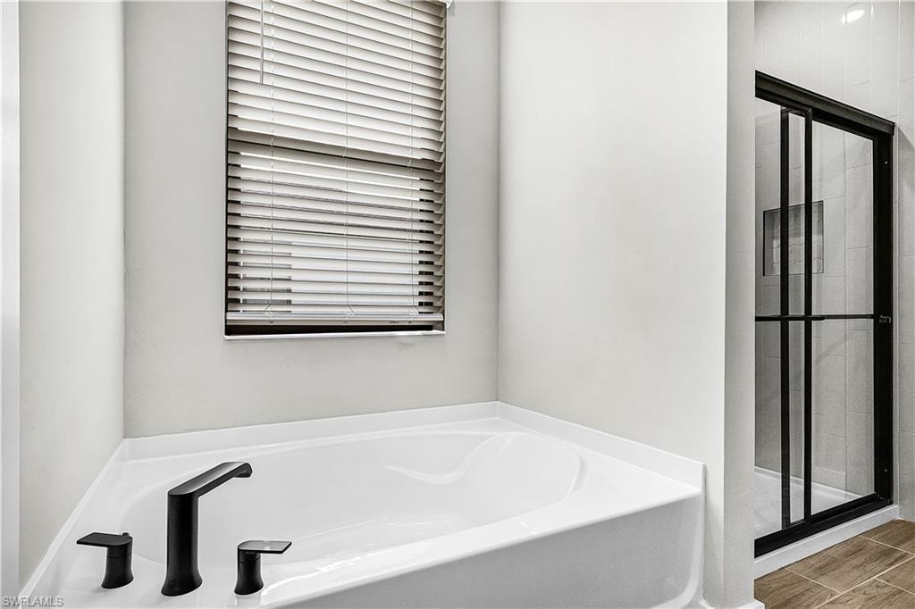 Full bath with a bath, a shower stall, and wood finish floors