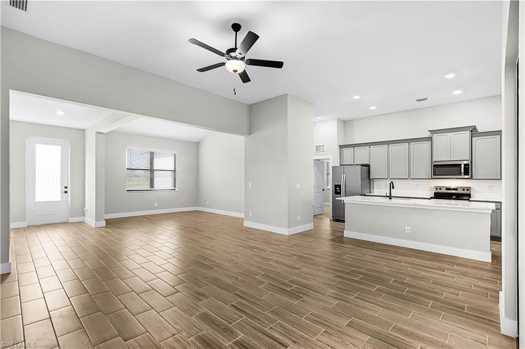 Unfurnished living room featuring ceiling fan, recessed lighting, and wood finish floors