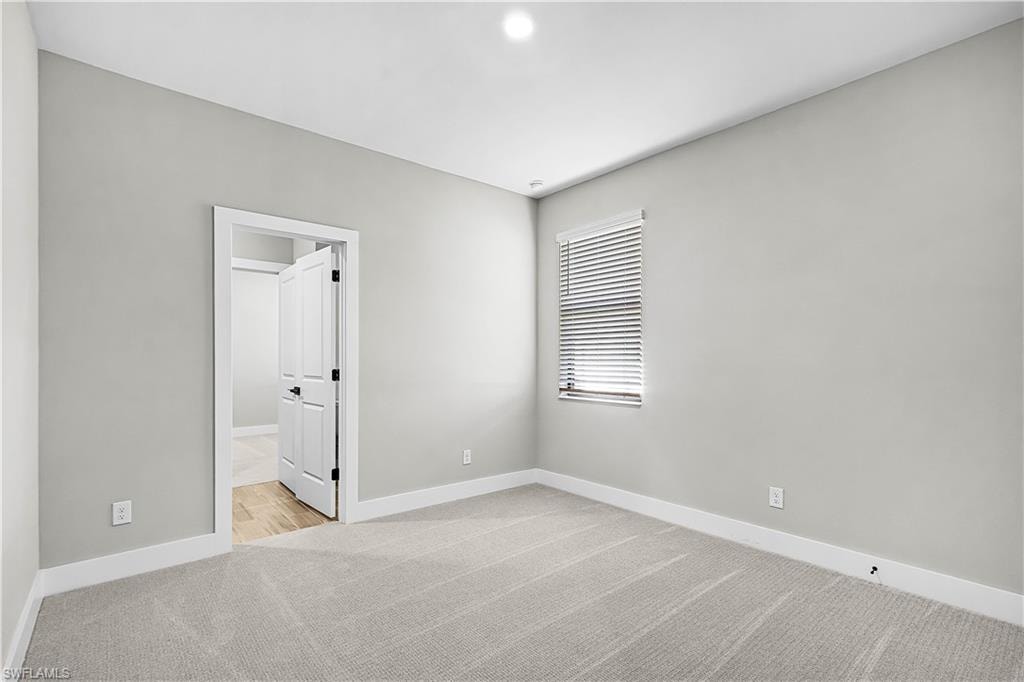 Unfurnished bedroom featuring light carpet and baseboards