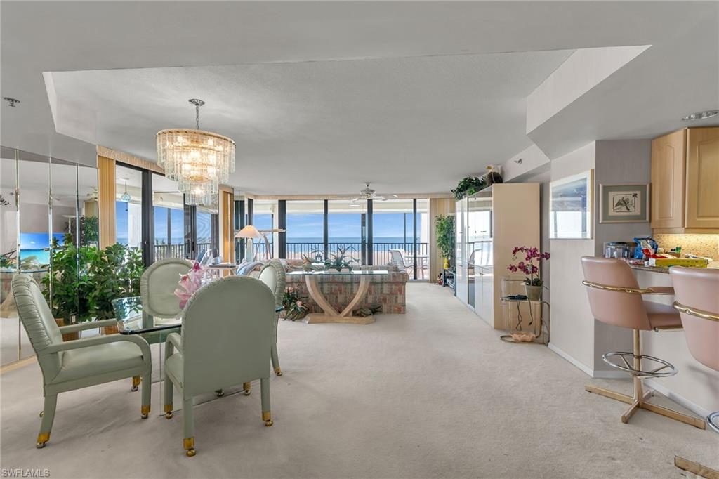 Dining space with baseboards, a wall of windows, carpet flooring, and a notable chandelier