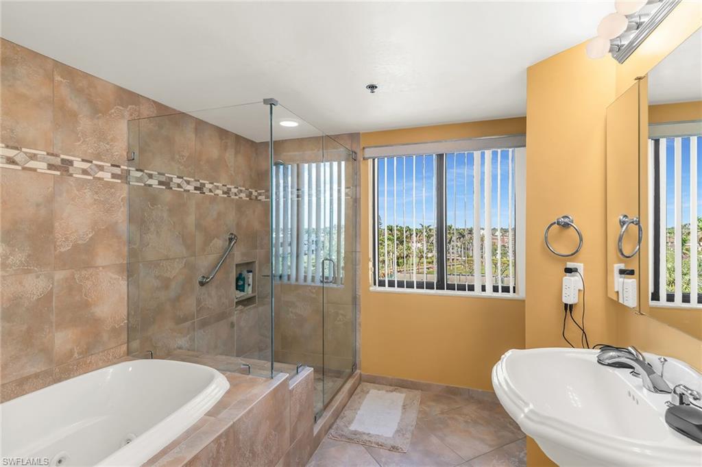 Full bath with baseboards, a tub with jets, tile patterned flooring, a shower stall, and a sink
