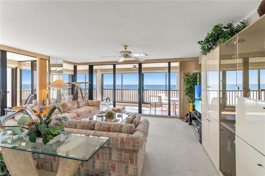 Living area featuring expansive windows, a ceiling fan, a textured ceiling, and light colored carpet
