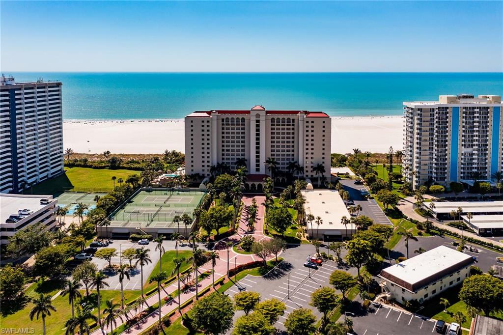 Birds eye view of property with a water view and a beach view