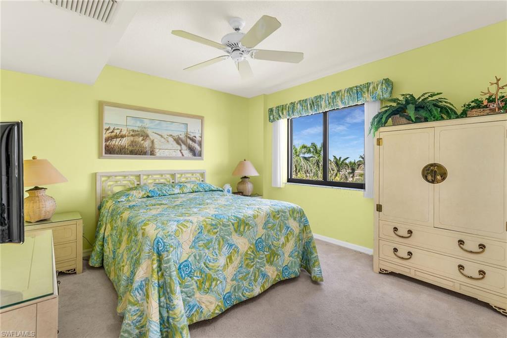 Bedroom with a ceiling fan, light colored carpet, visible vents, and baseboards
