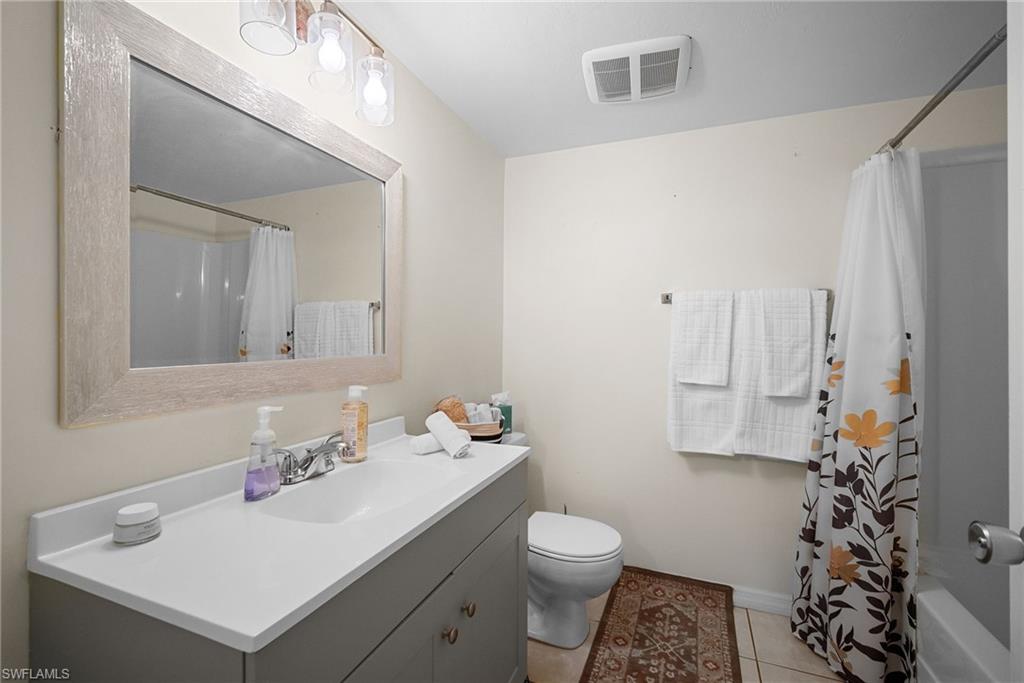 Full bathroom with light tile patterned floors, vanity, and shower / tub combo