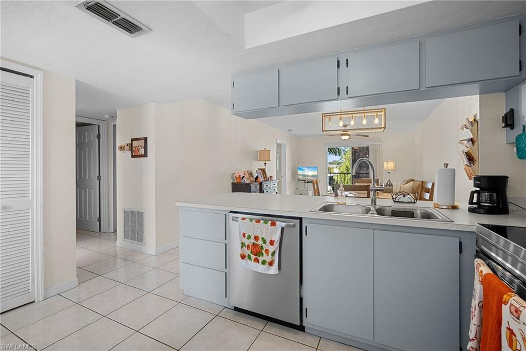 Kitchen featuring gray cabinets, stainless steel appliances, light countertops, a peninsula, and light tile patterned floors