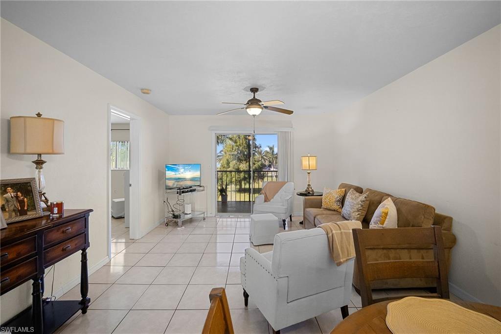 Tiled living room with a ceiling fan and baseboards