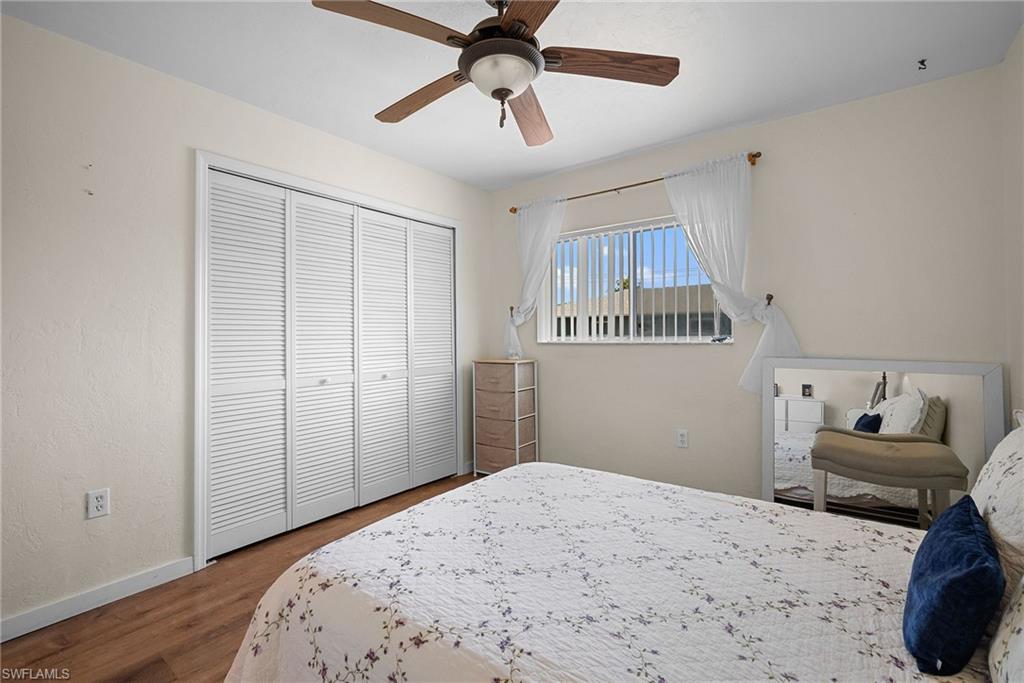 Bedroom with dark wood-style floors, a ceiling fan, and a closet