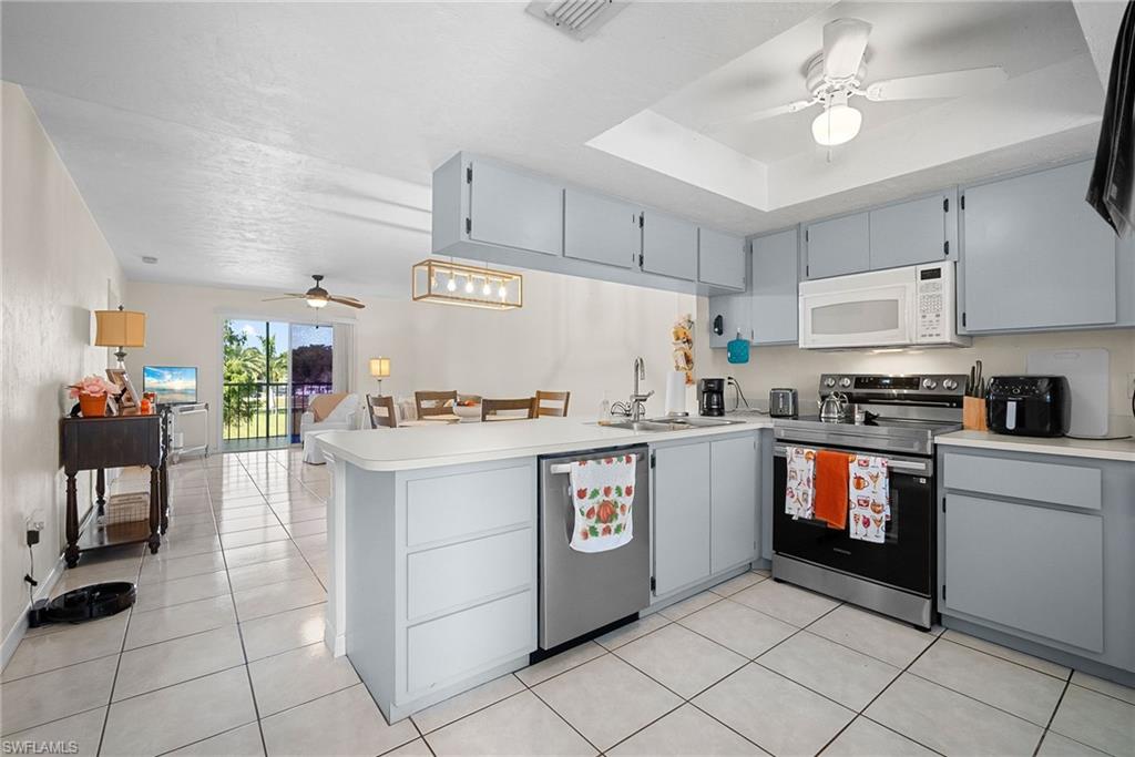 Kitchen featuring ceiling fan, gray cabinetry, stainless steel appliances, and a peninsula