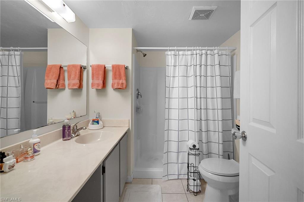 Bathroom with light tile patterned flooring, a stall shower, and vanity