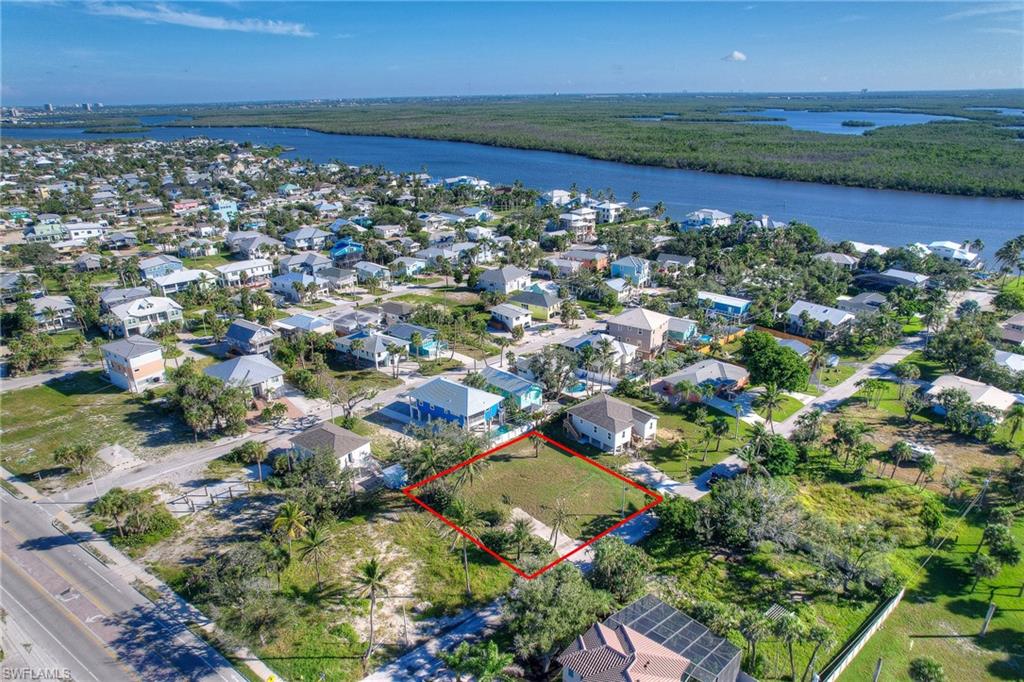 Aerial perspective of suburban area featuring property parcel outlined and a nearby body of water
