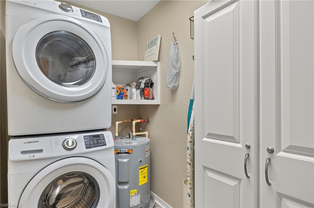 Laundry area featuring laundry area, stacked washer / dryer, and electric water heater