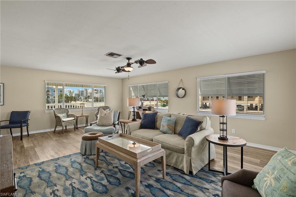 Living area with a ceiling fan, baseboards, visible vents, and wood finished floors