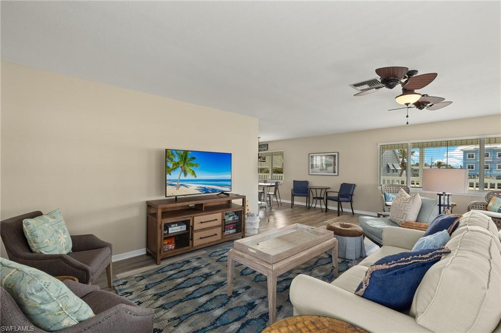 Living room with ceiling fan, wood finished floors, visible vents, and baseboards