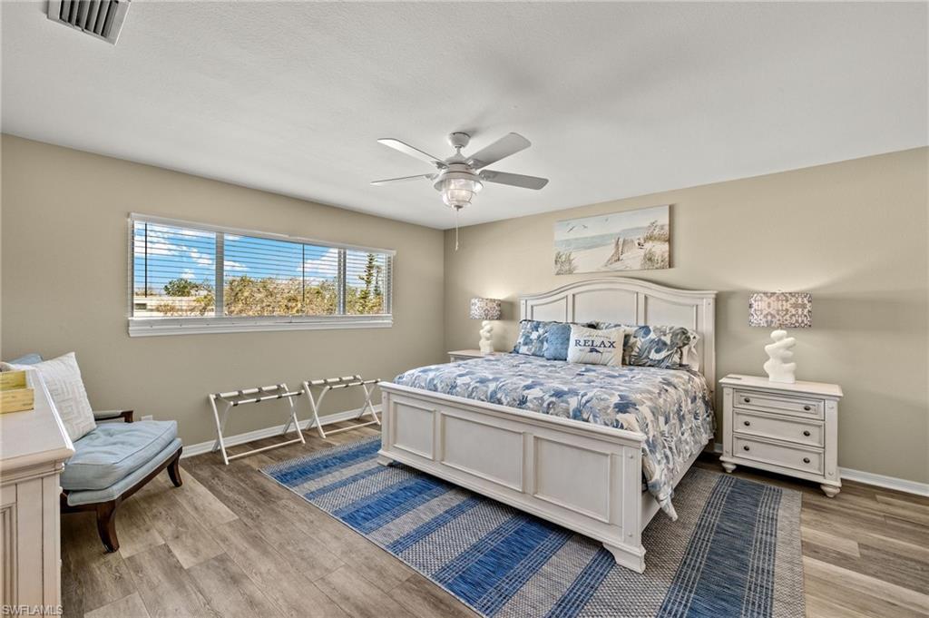 Bedroom featuring a ceiling fan, baseboards, visible vents, and wood finished floors