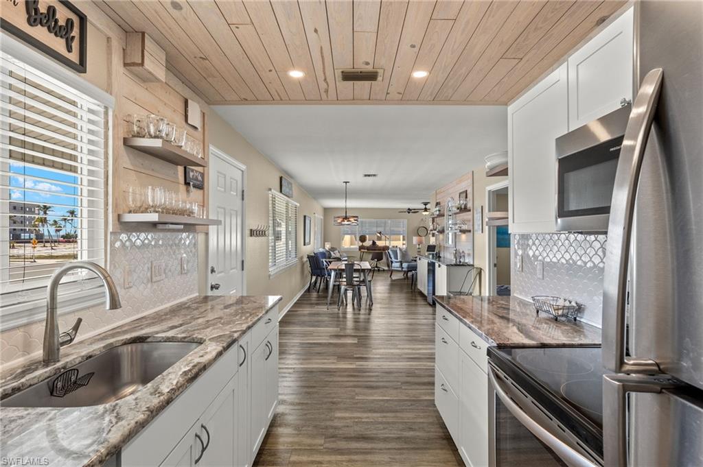 Kitchen featuring white cabinets, wooden ceiling, a sink, stainless steel appliances, and backsplash