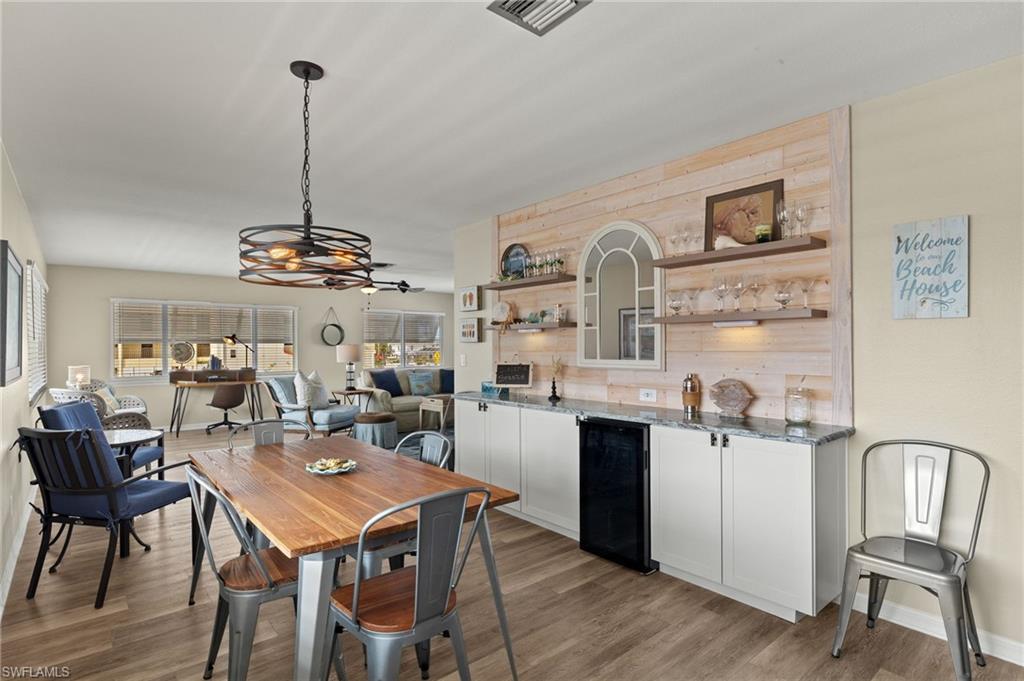 Dining space featuring light wood-style floors, wine cooler, and visible vents