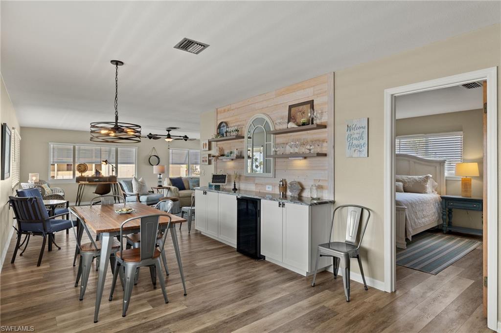 Dining space featuring beverage cooler, visible vents, indoor wet bar, and wood finished floors