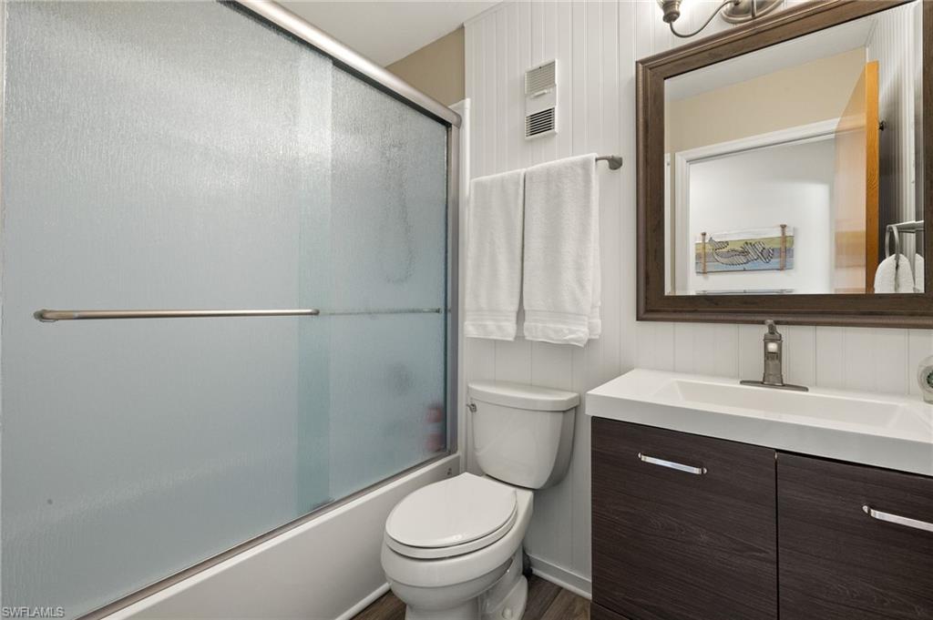 Full bath featuring shower / bath combination with glass door, vanity, and toilet