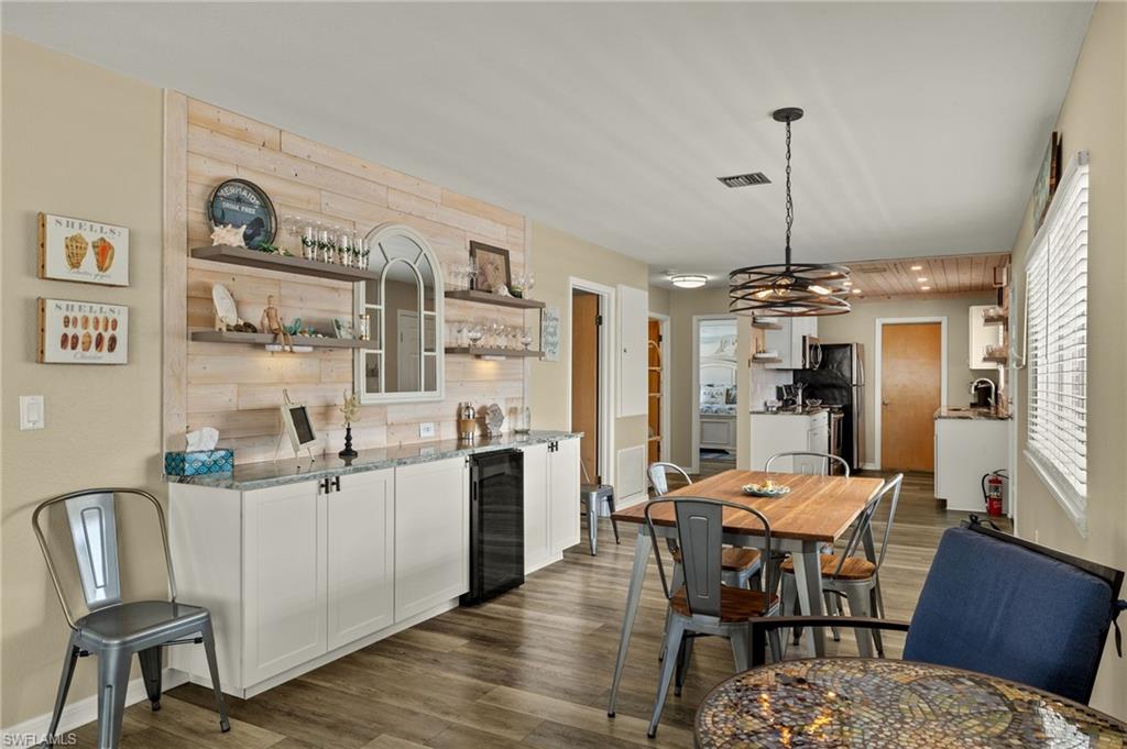 Dining space with beverage cooler, visible vents, baseboards, and dark wood-style flooring