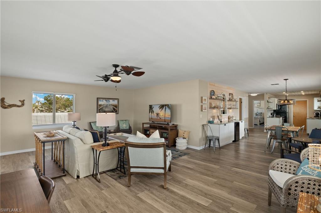 Living room with ceiling fan, light wood-style flooring, and baseboards