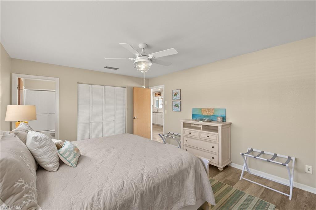 Bedroom with a closet, visible vents, ceiling fan, wood finished floors, and baseboards