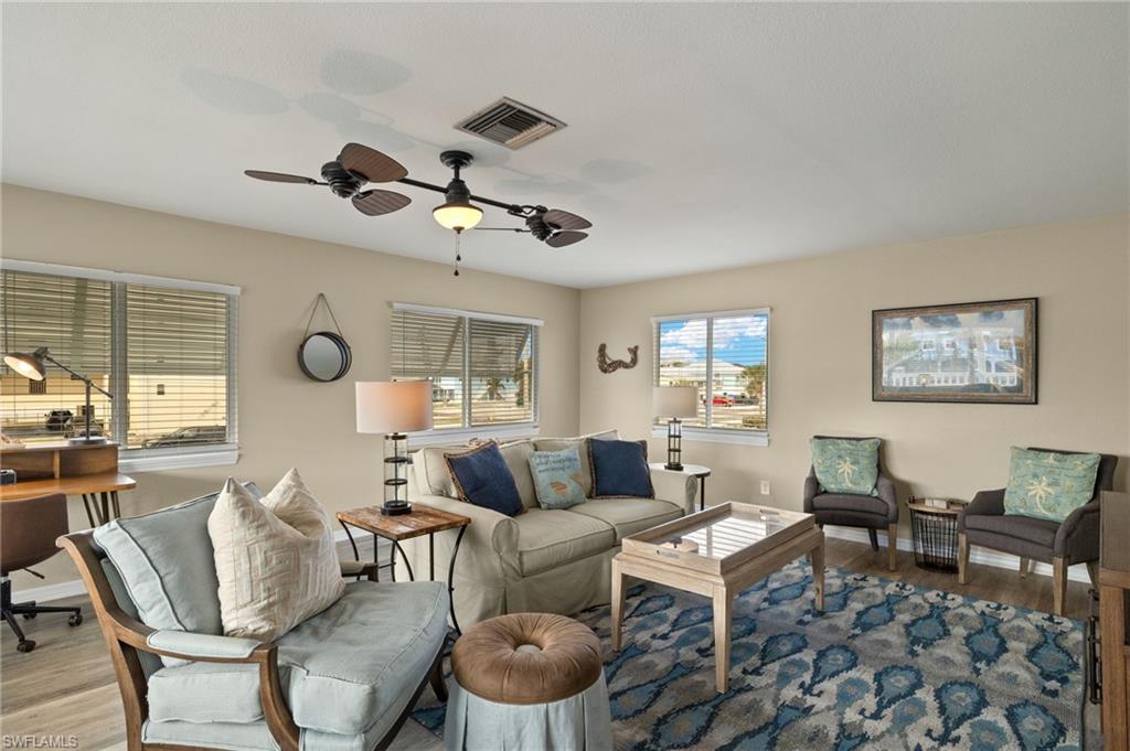 Living area with a ceiling fan, baseboards, visible vents, and wood finished floors