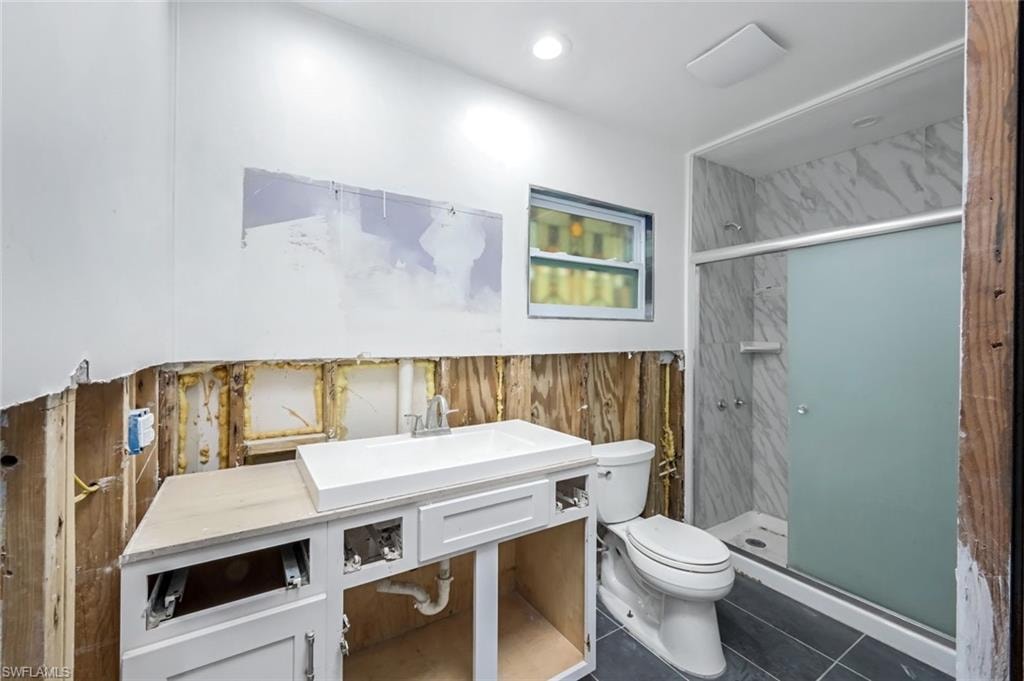 Bathroom with recessed lighting, toilet, vanity, a shower stall, and tile patterned floors