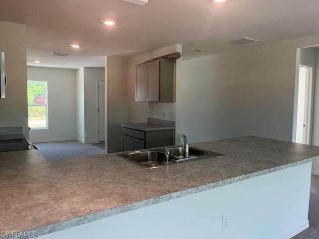 Kitchen with a peninsula, dark carpet, recessed lighting, gray cabinets, and range