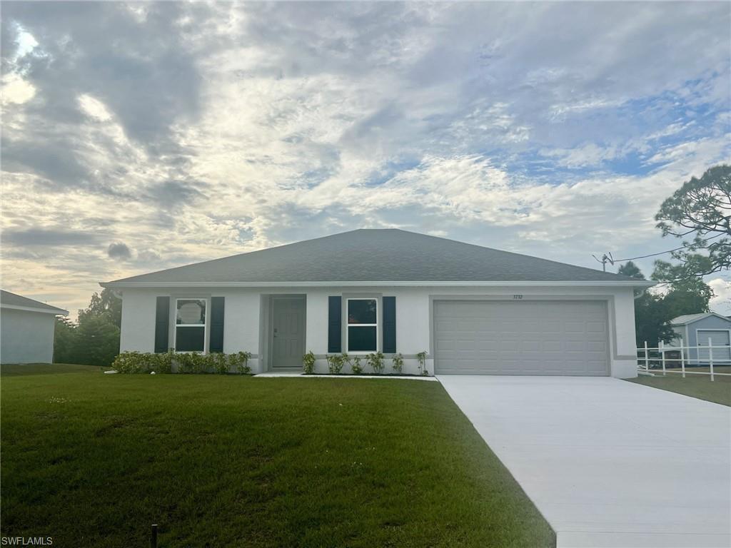 Ranch-style home featuring a front yard, concrete driveway, and an attached garage