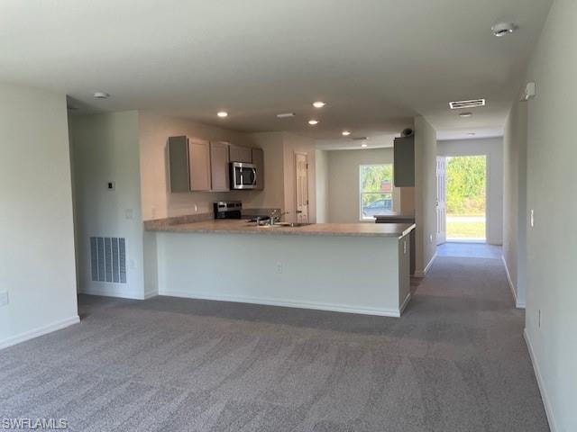 Kitchen with dark colored carpet, a peninsula, appliances with stainless steel finishes, recessed lighting, and open floor plan
