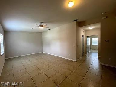 Tiled spare room with visible vents, plenty of natural light, baseboards, and ceiling fan