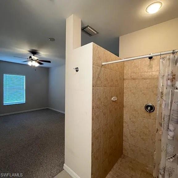 Full bath with visible vents, baseboards, ceiling fan, and a tile shower