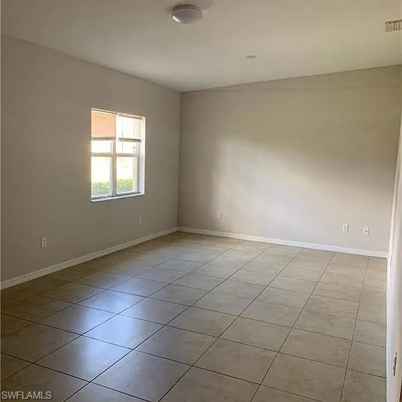 Spare room with light tile patterned flooring, visible vents, and baseboards