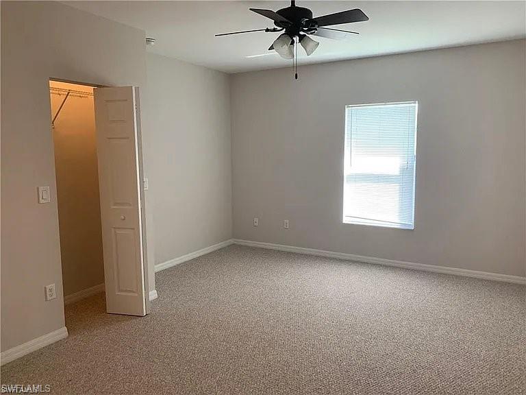 Spare room with light colored carpet, baseboards, and ceiling fan